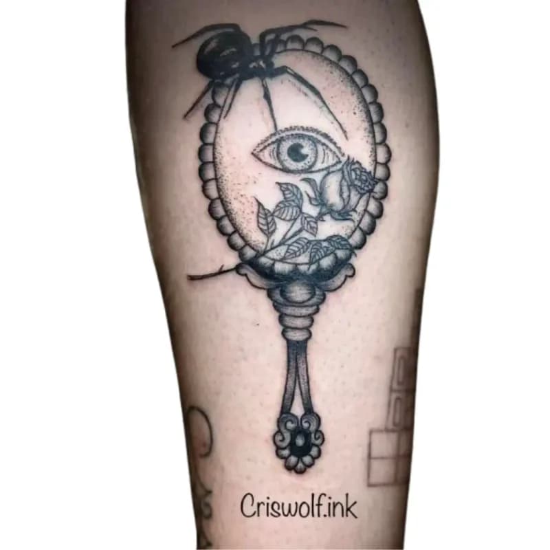 Tatouage miroir à main orné d'un œil et d'une rose sur jambe, Le Papillon Qui Pique Montbéliard